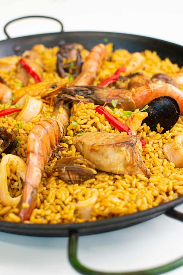 Qual è il metodo per cuocere una paella ai frutti di mare con riso bomba?
